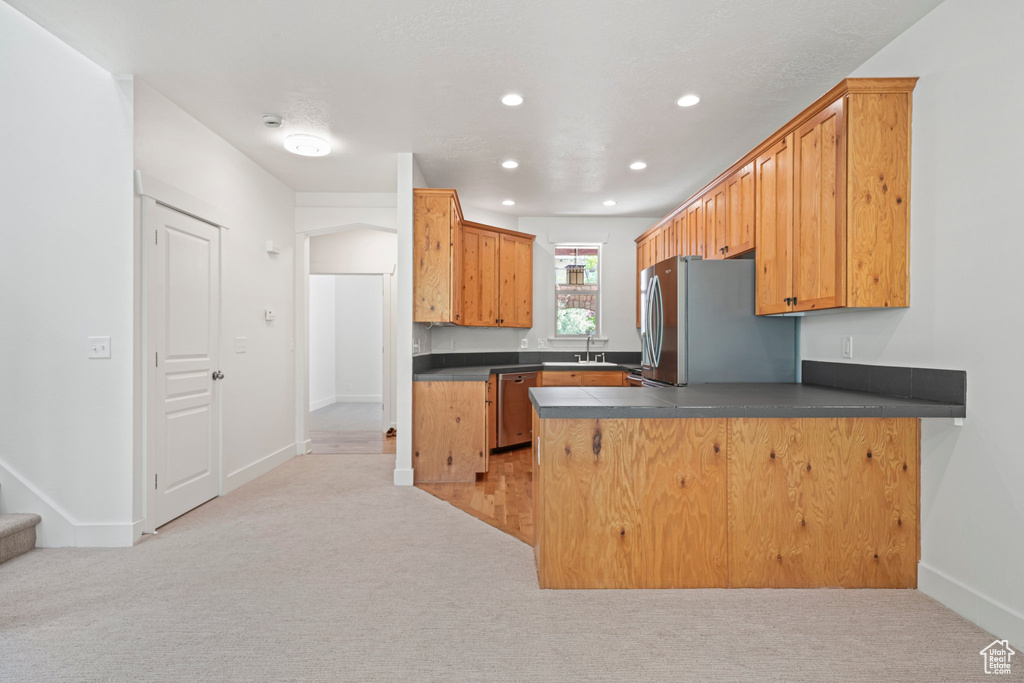 Kitchen with light colored carpet, sink, kitchen peninsula, and stainless steel appliances