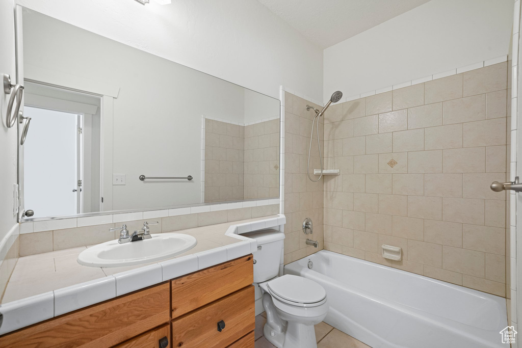 Full bathroom featuring tile flooring, vanity, tiled shower / bath combo, and toilet