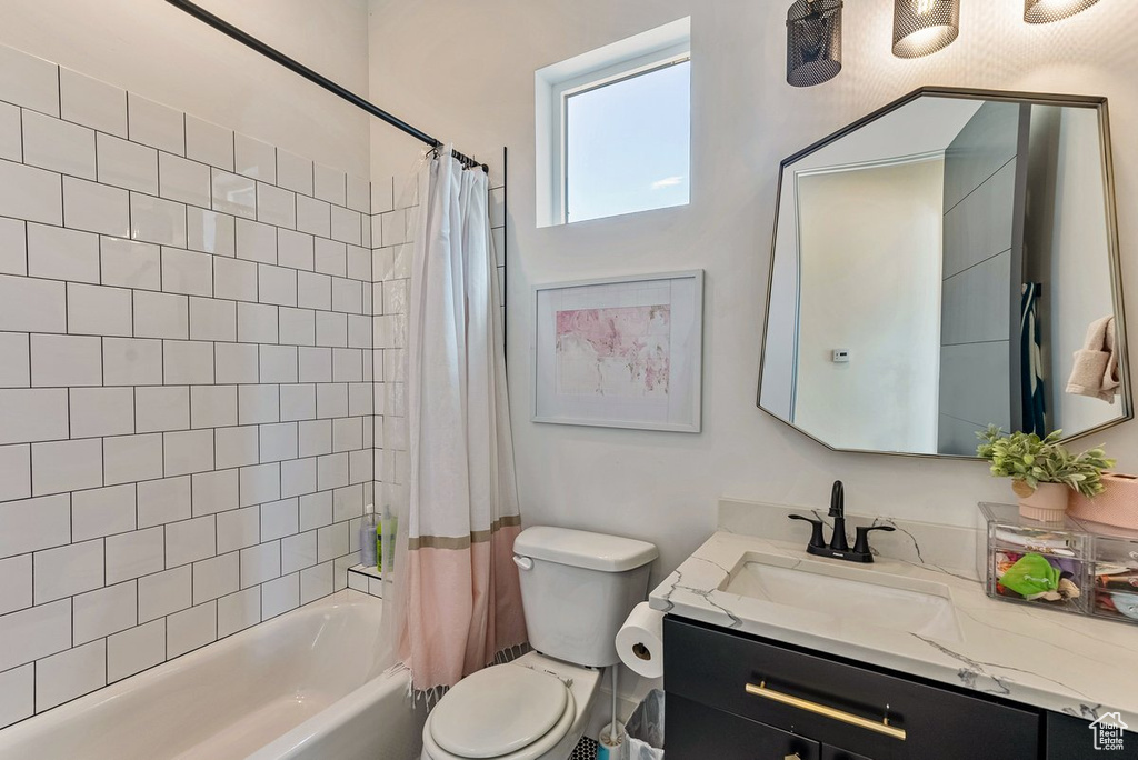 Full bathroom featuring vanity with extensive cabinet space, shower / bathtub combination with curtain, and toilet