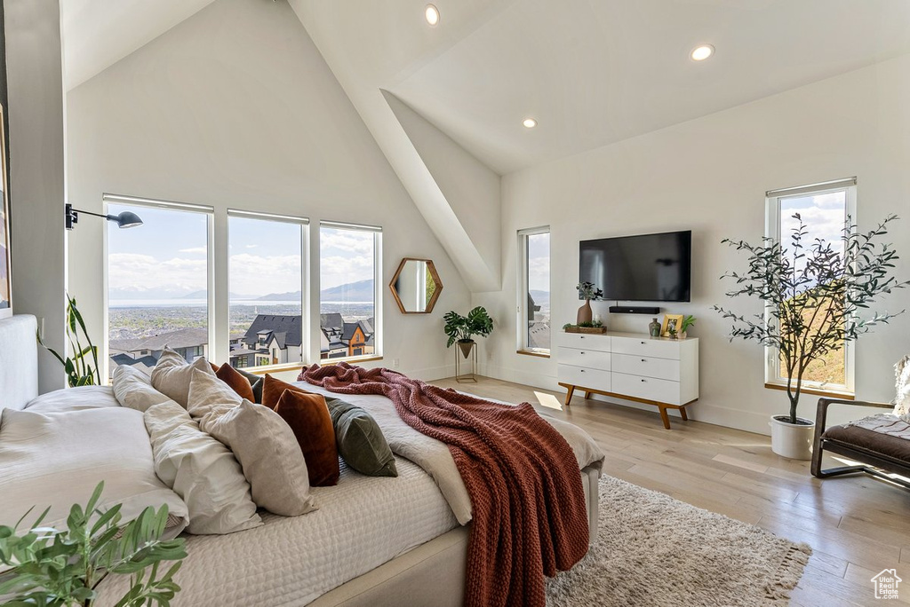 Bedroom with high vaulted ceiling and light hardwood / wood-style floors