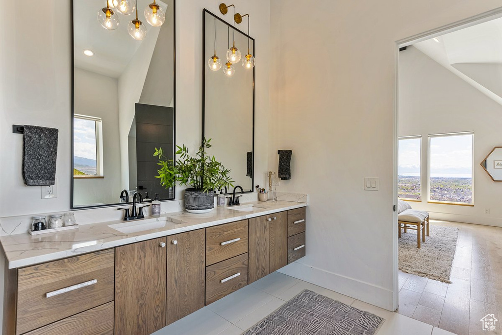 Bathroom featuring hardwood / wood-style floors, a chandelier, high vaulted ceiling, and dual bowl vanity