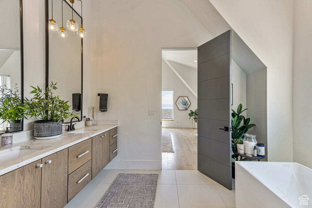 Bathroom featuring a bath to relax in, high vaulted ceiling, tile floors, and double sink vanity