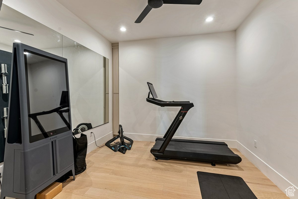 Exercise room with light hardwood / wood-style floors and ceiling fan