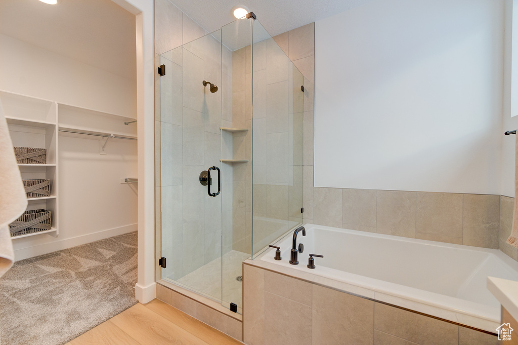 Bathroom with hardwood / wood-style flooring and shower with separate bathtub