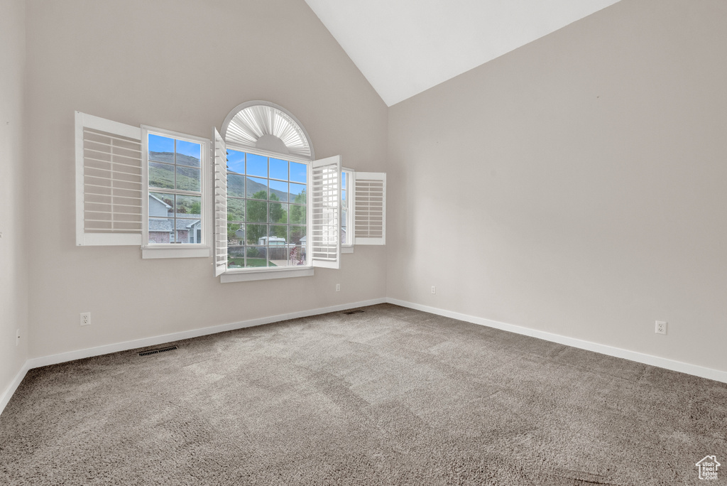 Carpeted empty room with high vaulted ceiling