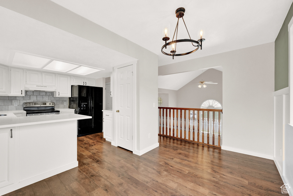 Kitchen featuring ceiling fan with notable chandelier, black refrigerator with ice dispenser, hardwood / wood-style floors, backsplash, and stainless steel range with electric cooktop