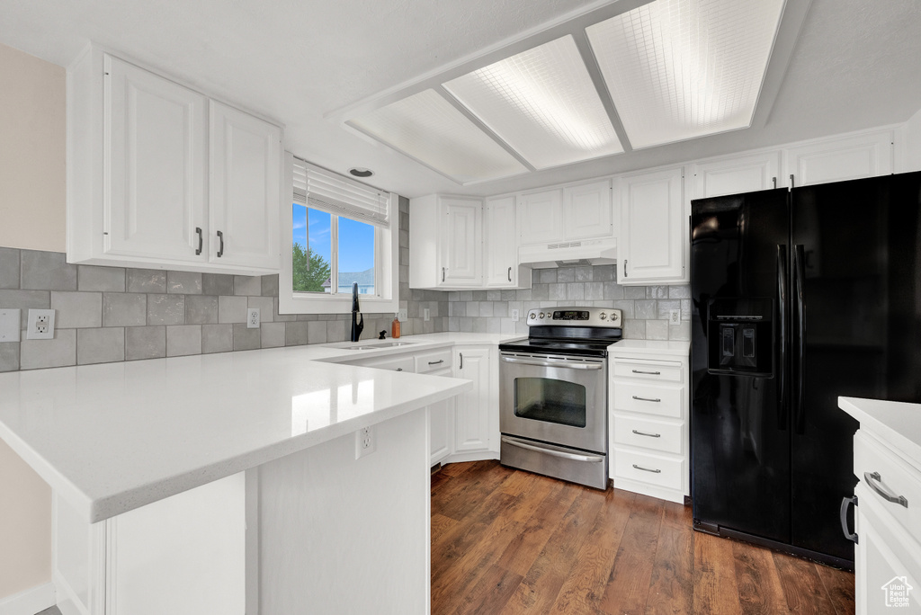 Kitchen with black fridge, stainless steel electric range, dark hardwood / wood-style floors, custom range hood, and sink