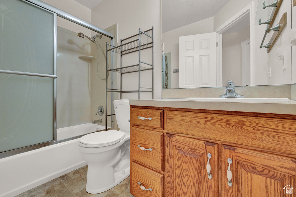 Full bathroom with toilet, shower / bath combination with glass door, vanity, and tile flooring