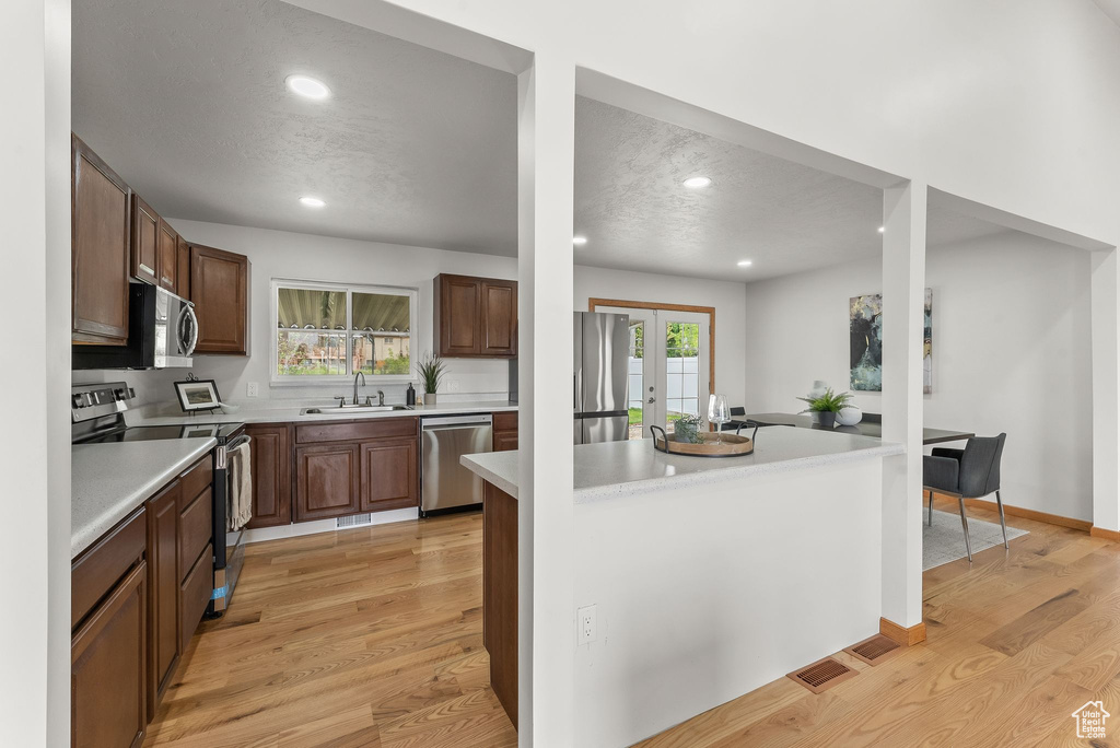 Kitchen featuring french doors, appliances with stainless steel finishes, light hardwood / wood-style floors, and sink