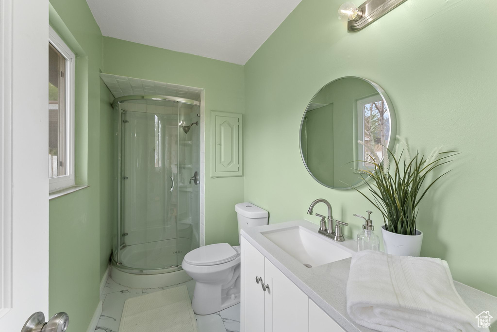 Bathroom featuring tile floors, vanity, toilet, and a shower with shower door
