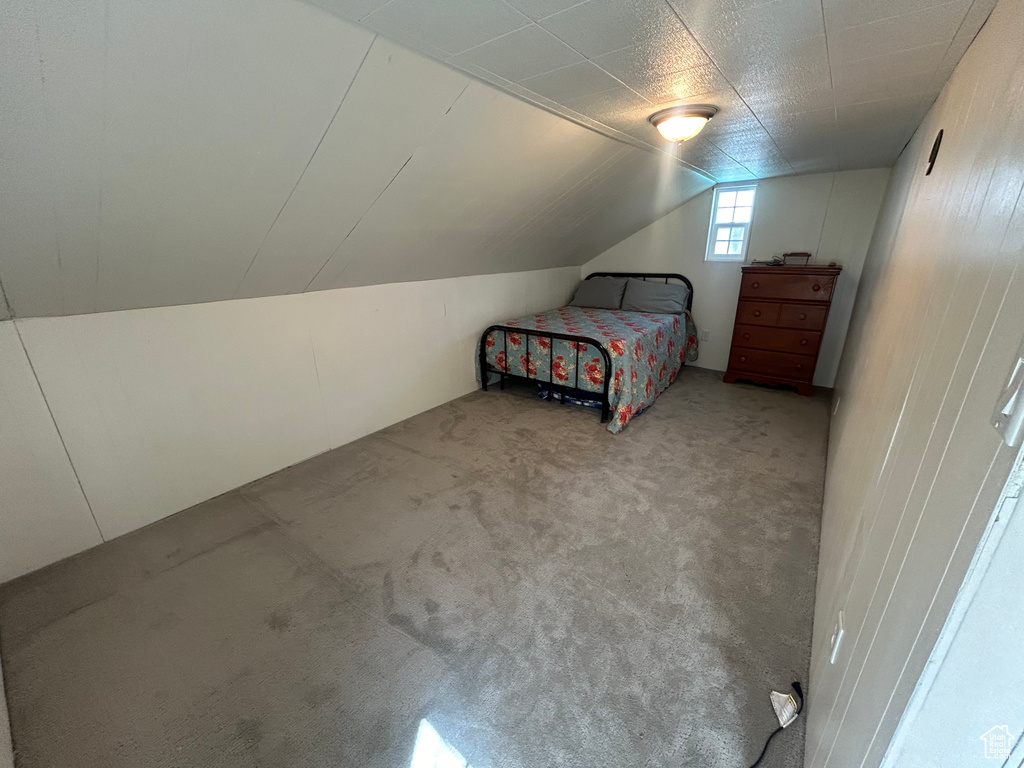 Unfurnished bedroom featuring carpet flooring and vaulted ceiling