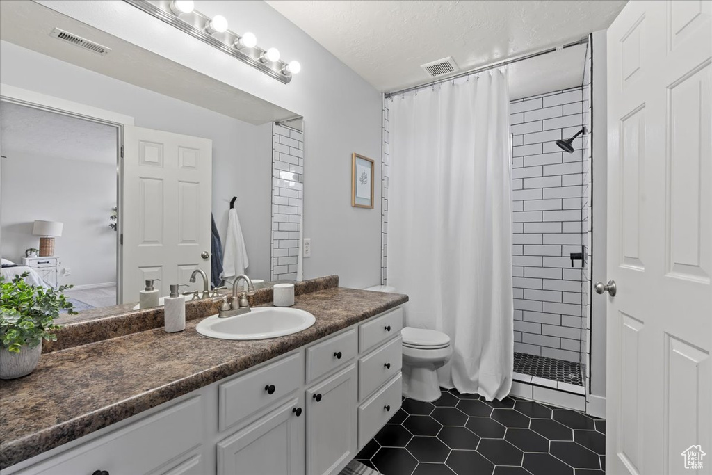 Bathroom featuring tile flooring, vanity, toilet, and a shower with shower curtain