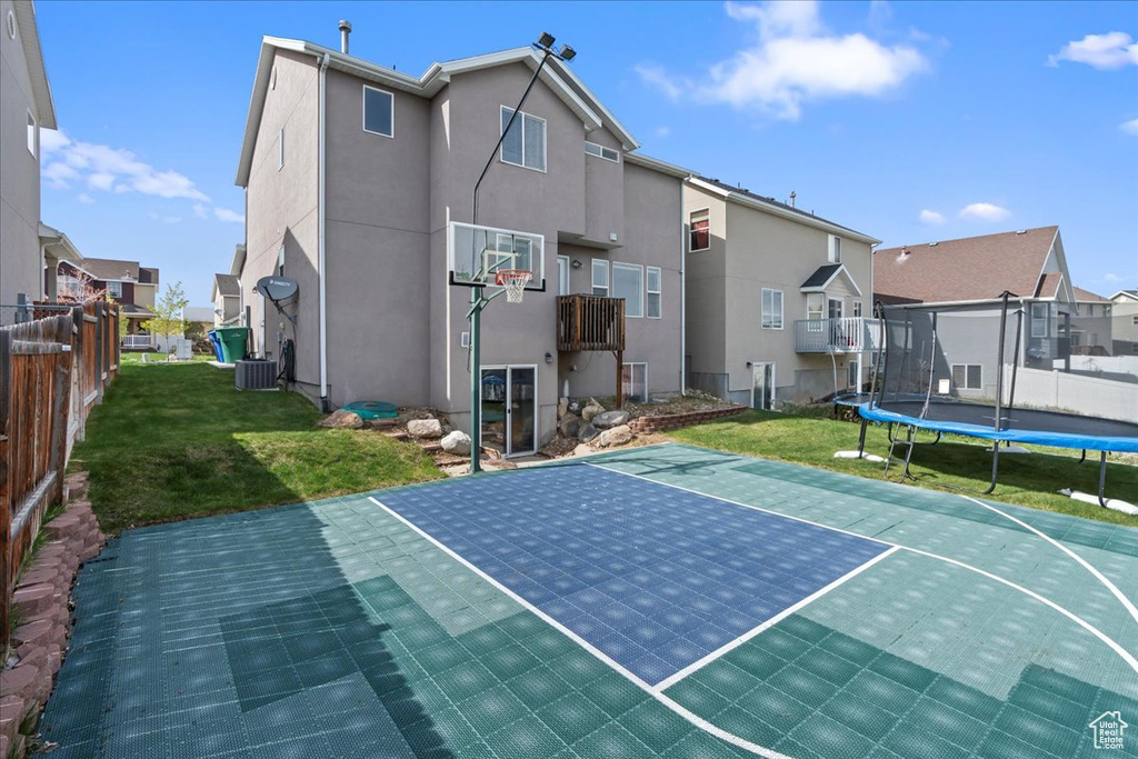 View of basketball court with a yard and a trampoline