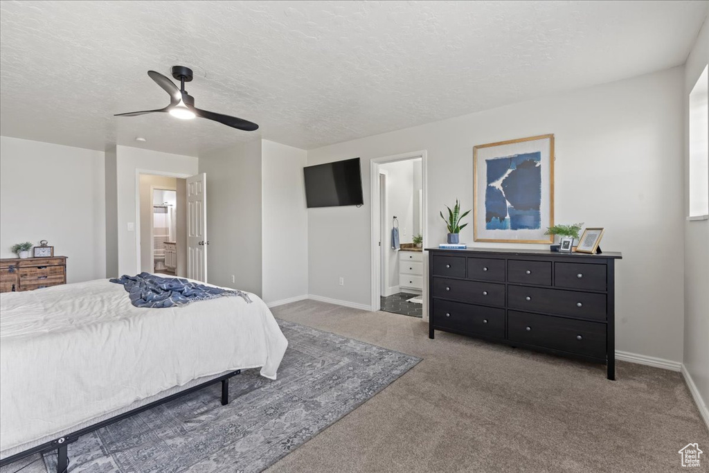 Carpeted bedroom featuring ensuite bath, ceiling fan, and a textured ceiling