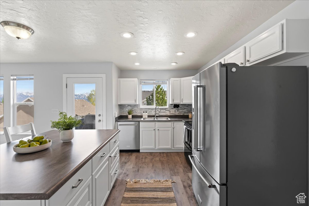 Kitchen featuring white cabinets, dark hardwood / wood-style floors, stainless steel appliances, sink, and tasteful backsplash