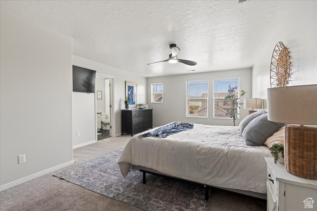 Carpeted bedroom with connected bathroom, ceiling fan, and a textured ceiling