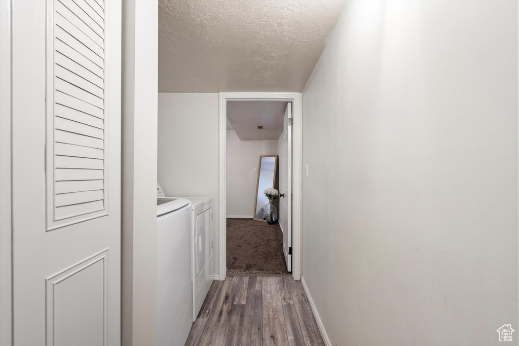Hallway featuring a textured ceiling, separate washer and dryer, and hardwood / wood-style floors