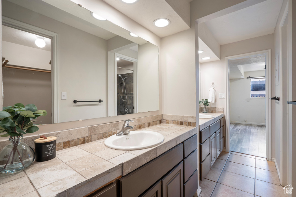 Bathroom featuring dual sinks, vanity with extensive cabinet space, and tile floors