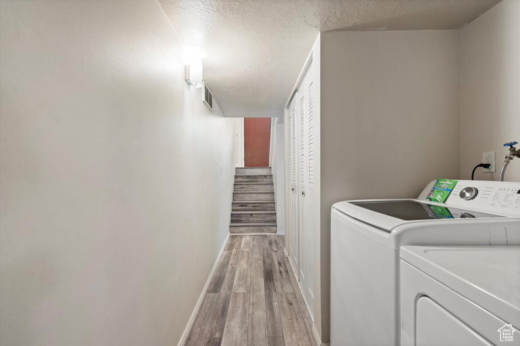 Laundry area featuring wood-type flooring, a textured ceiling, and washer and dryer