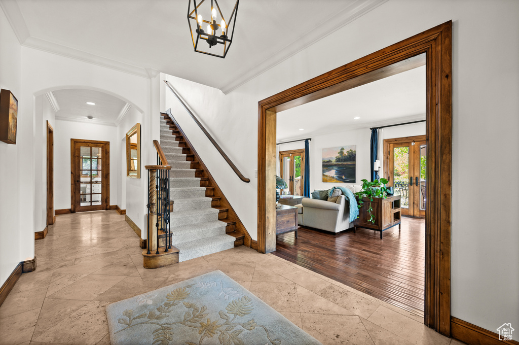 Foyer entrance featuring a notable chandelier, crown molding, and tile floors