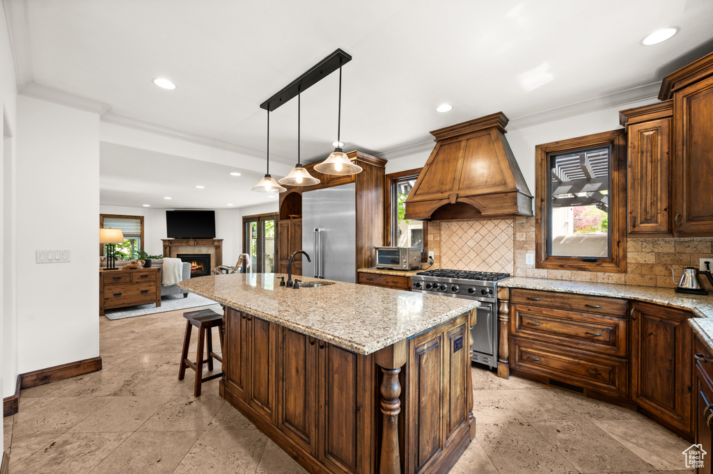 Kitchen featuring light tile flooring, custom exhaust hood, an island with sink, and high quality appliances