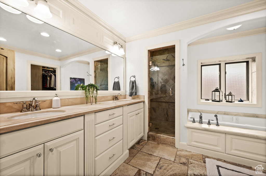 Bathroom featuring ornamental molding, double vanity, shower with separate bathtub, and tile flooring