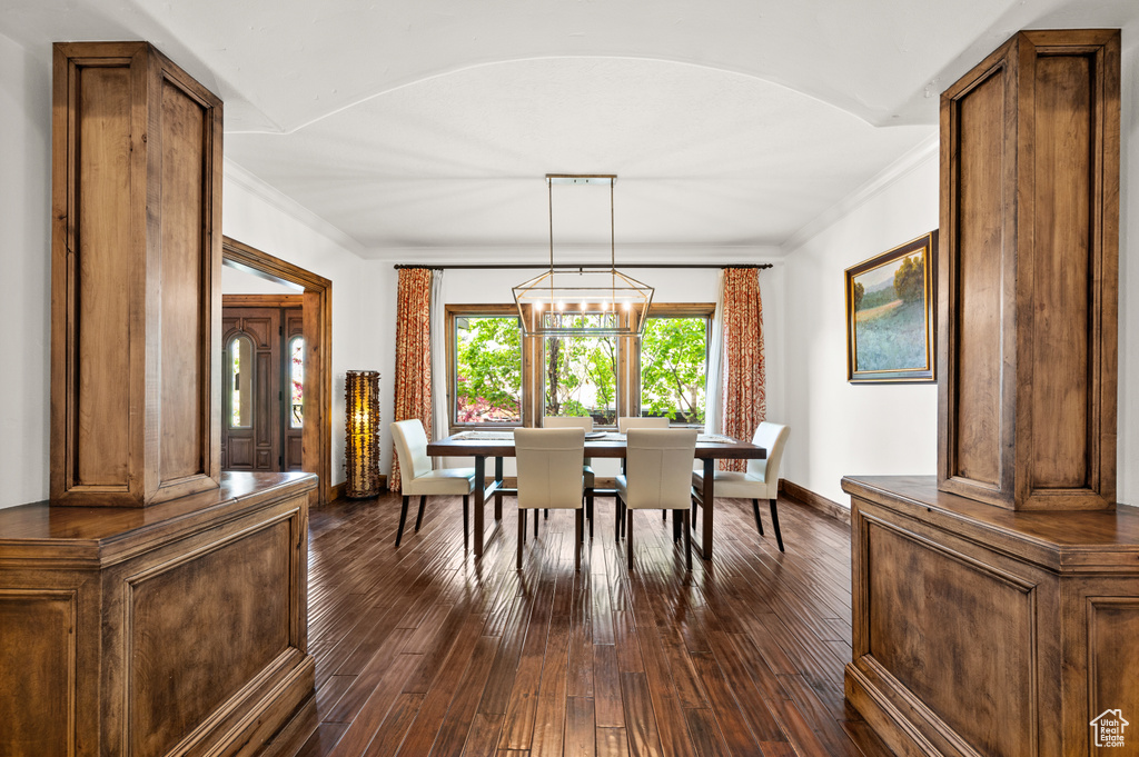 Dining space featuring ornamental molding, dark hardwood / wood-style flooring, and a notable chandelier