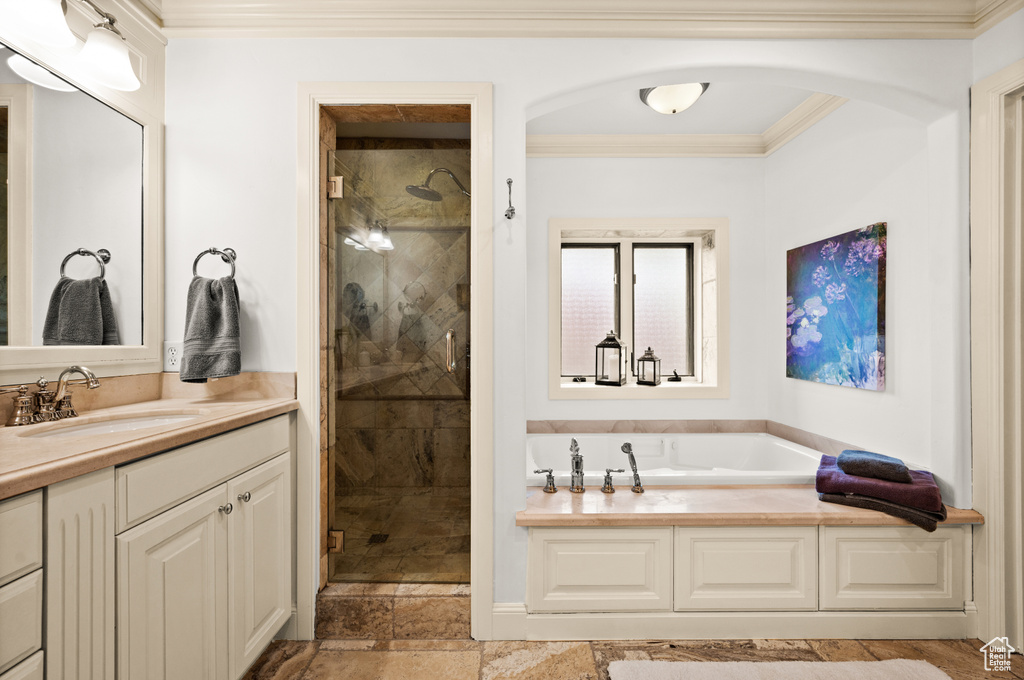 Bathroom with vanity with extensive cabinet space, ornamental molding, tile floors, and separate shower and tub