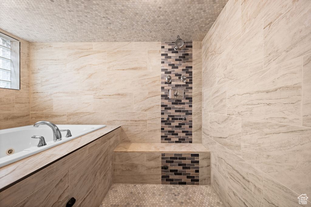 Bathroom featuring tile walls and plus walk in shower