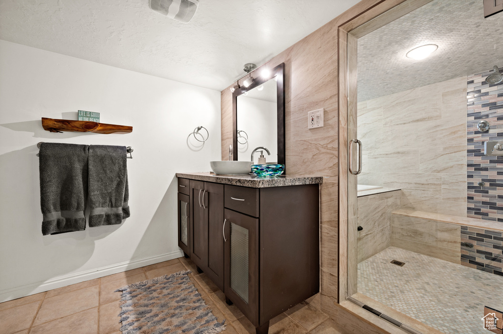 Bathroom featuring walk in shower, a textured ceiling, vanity, and tile flooring