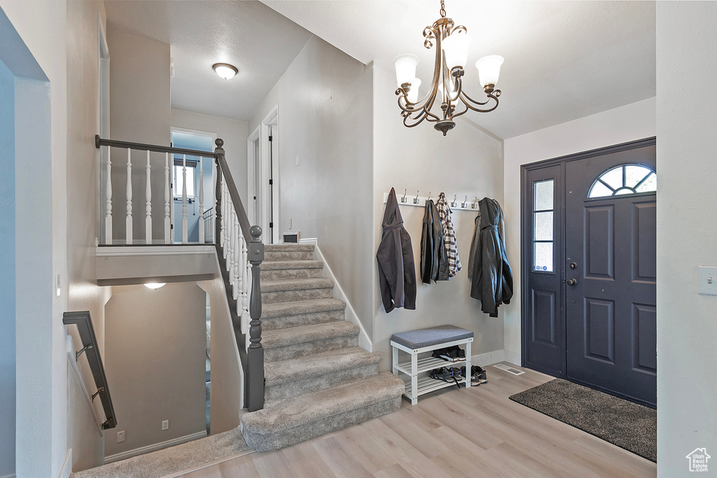 Entryway with light hardwood / wood-style floors and an inviting chandelier