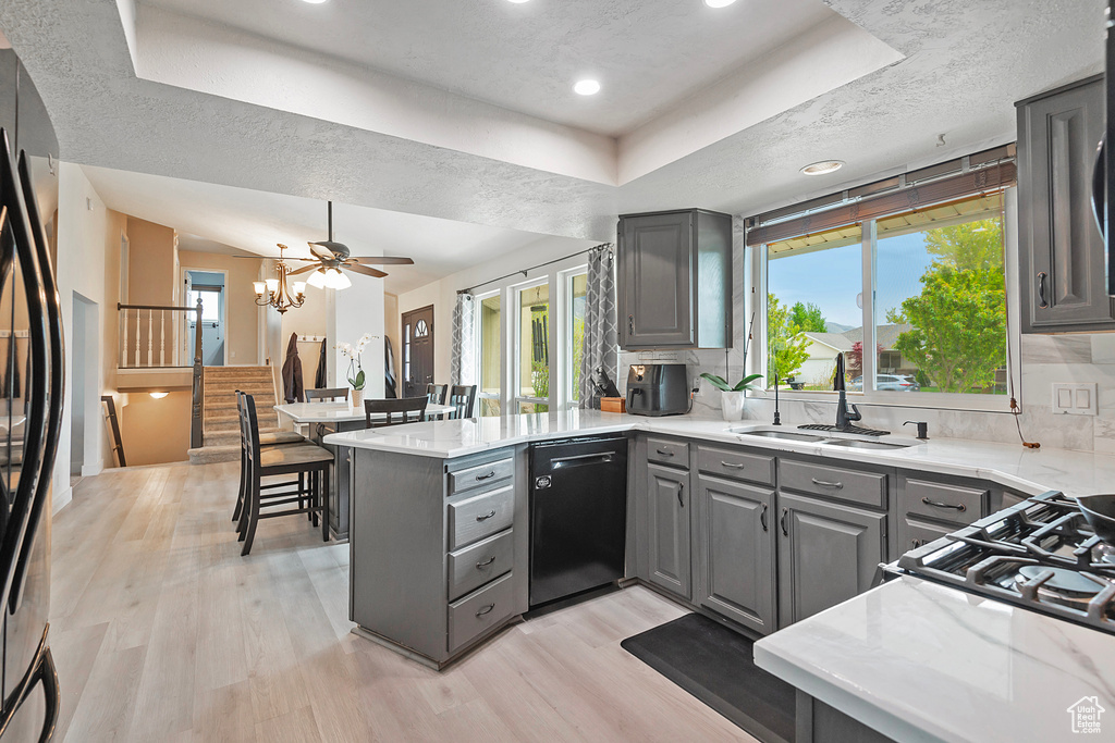 Kitchen with backsplash, black dishwasher, kitchen peninsula, and gray cabinetry