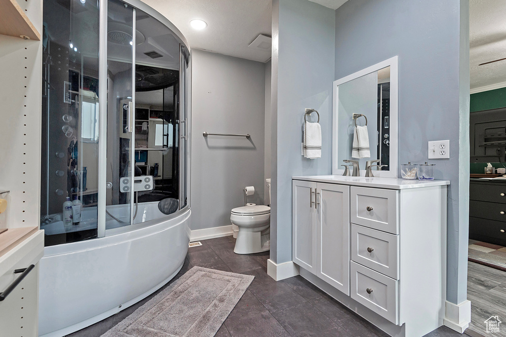 Bathroom with toilet, vanity with extensive cabinet space, and tile flooring