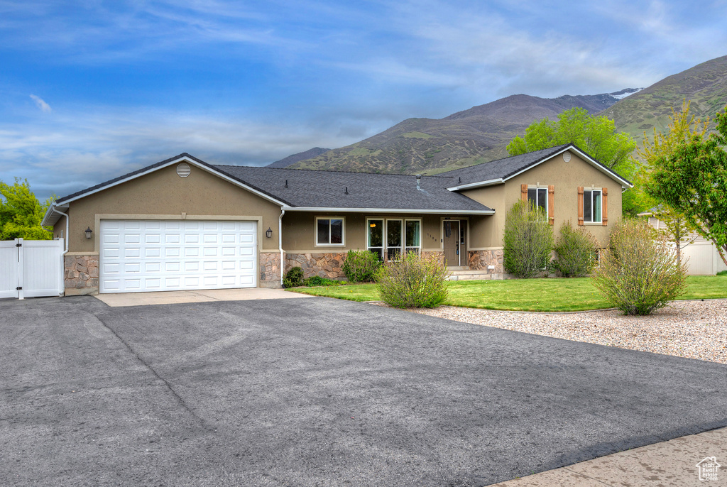 Ranch-style house with a garage, a mountain view, and a front lawn