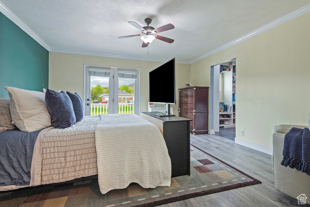 Bedroom featuring ceiling fan, access to exterior, wood-type flooring, a textured ceiling, and ornamental molding