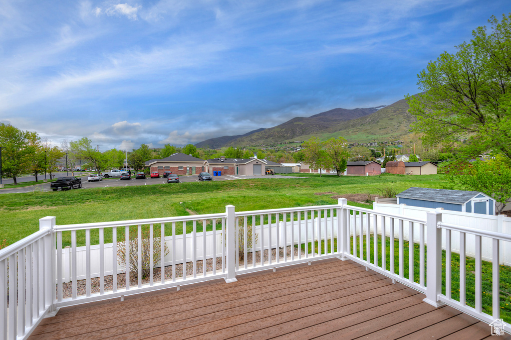 Wooden deck featuring a shed, a mountain view, and a lawn