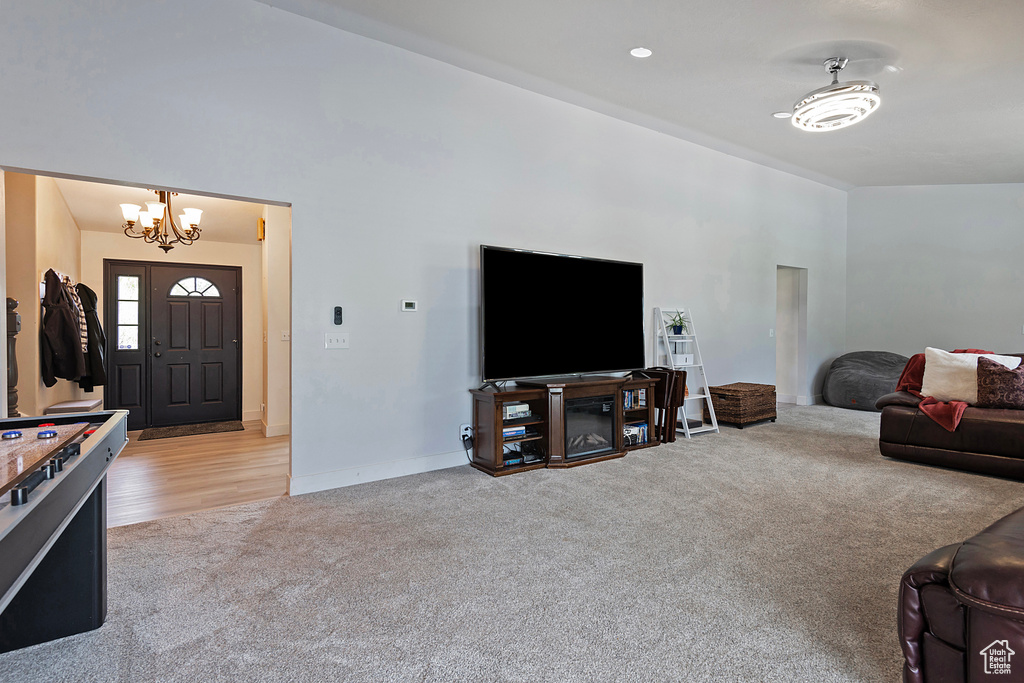 Living room with vaulted ceiling, a notable chandelier, and light carpet