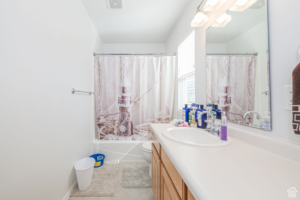 Full bathroom featuring tile floors, vanity with extensive cabinet space, toilet, and shower / bathtub combination with curtain