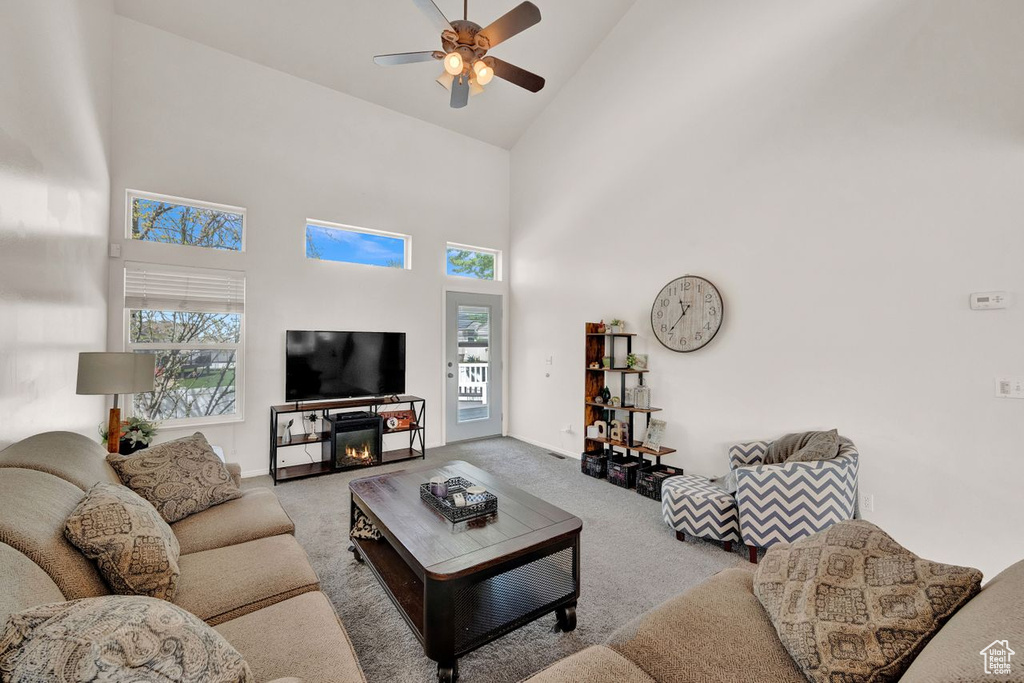 Carpeted living room with high vaulted ceiling and ceiling fan