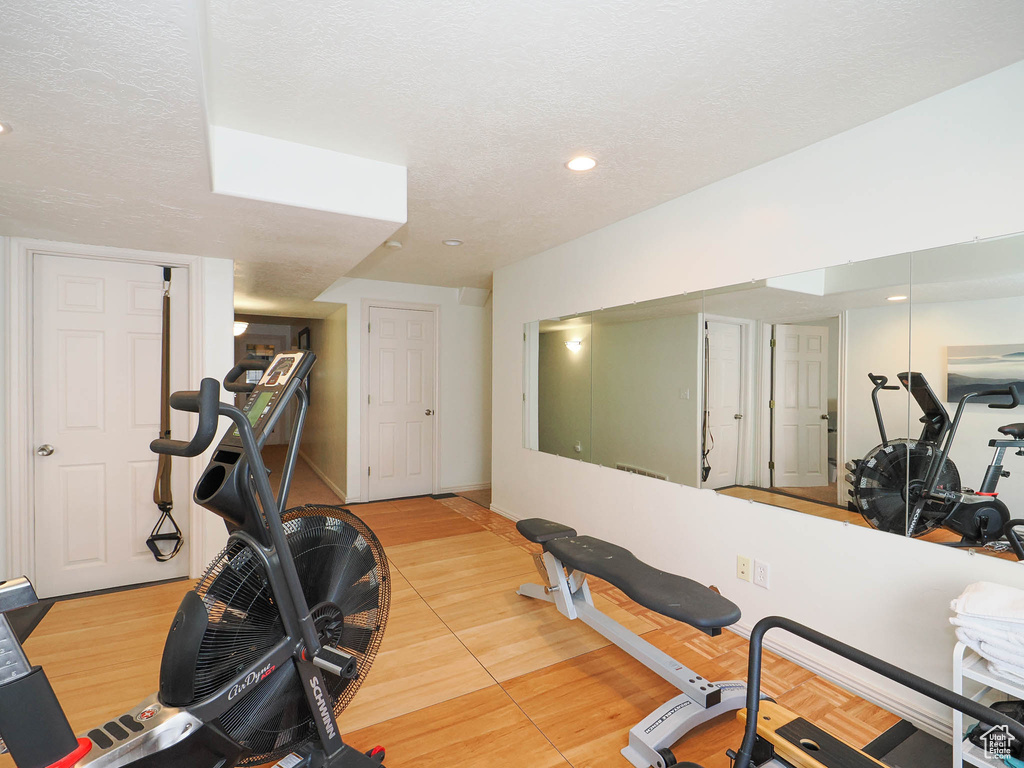 Workout area featuring light hardwood / wood-style flooring and a textured ceiling