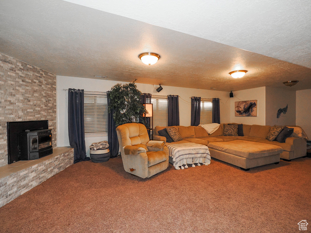 Living room featuring a textured ceiling, a wood stove, and carpet