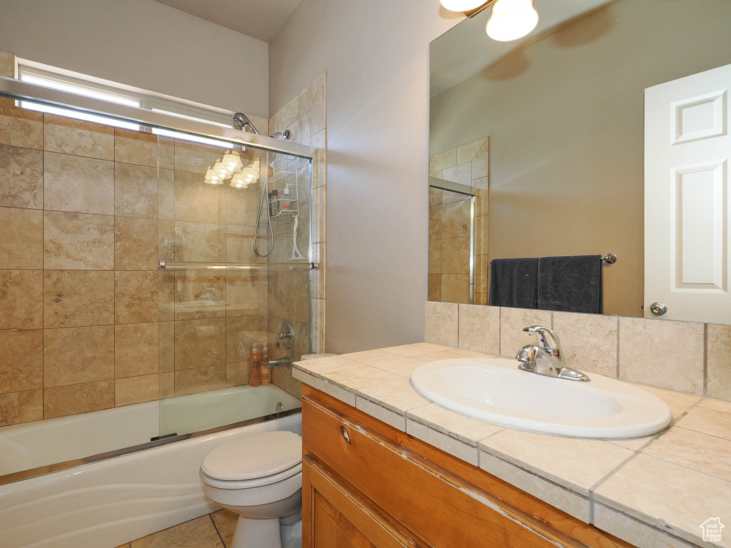Full bathroom featuring enclosed tub / shower combo, tile flooring, toilet, and large vanity