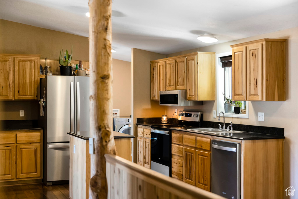 Kitchen featuring appliances with stainless steel finishes, dark hardwood / wood-style flooring, washer / clothes dryer, and sink