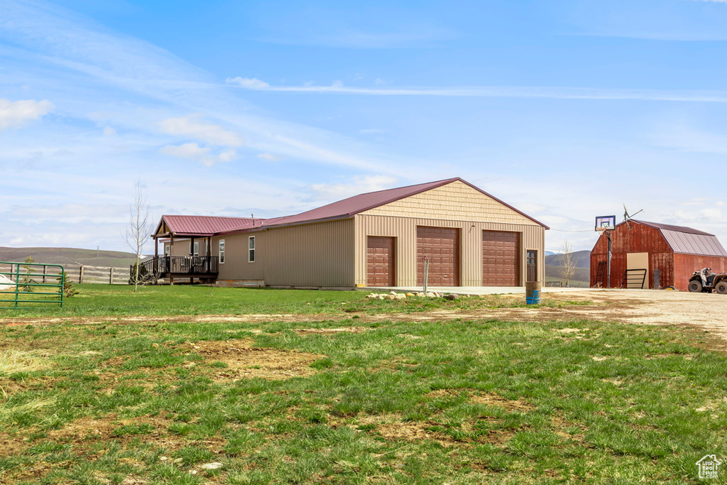 View of side of property with an outdoor structure, a garage, and a lawn