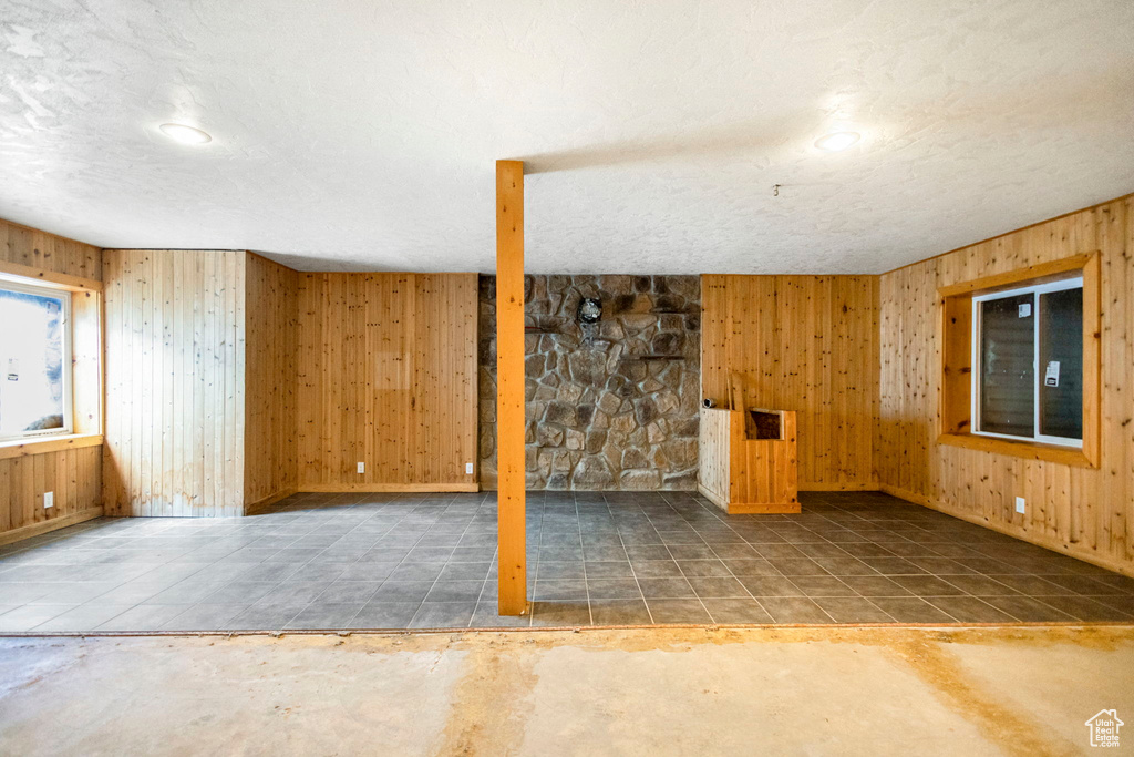 Basement featuring a textured ceiling, wood walls, and tile floors