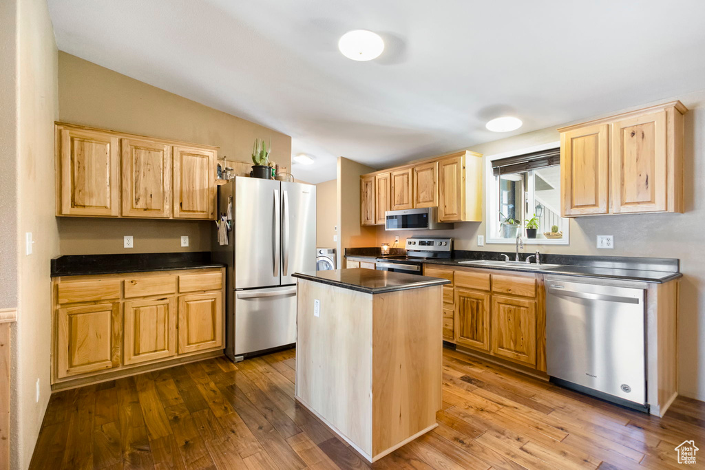 Kitchen with sink, a kitchen island, hardwood / wood-style flooring, and stainless steel appliances