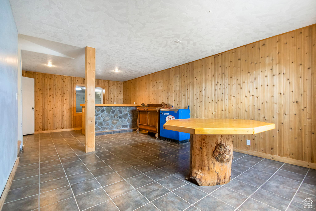 Playroom featuring wood walls, dark tile floors, and a textured ceiling