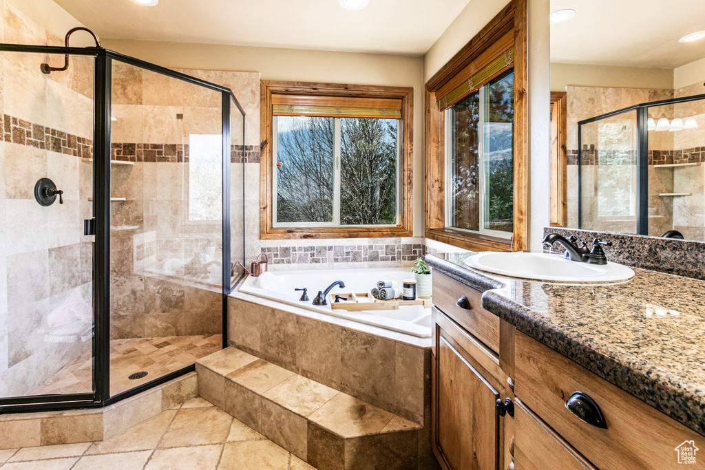 Bathroom featuring vanity with extensive cabinet space, shower with separate bathtub, and tile floors