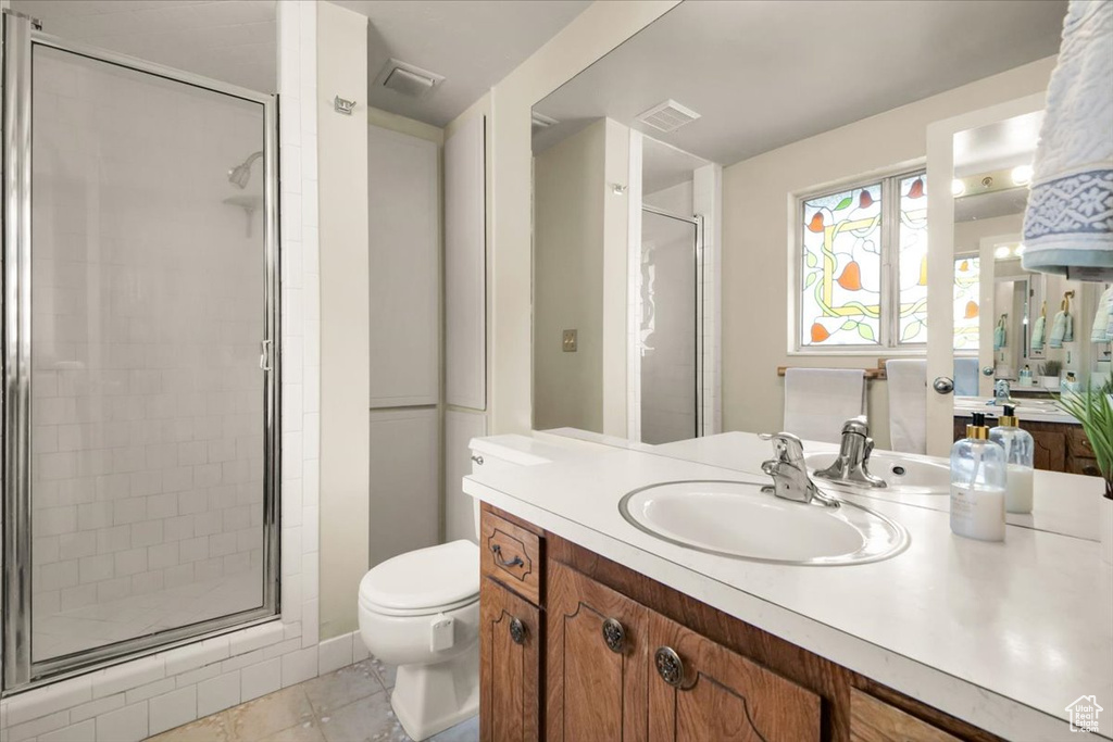 Bathroom with an enclosed shower, tile floors, toilet, and vanity with extensive cabinet space