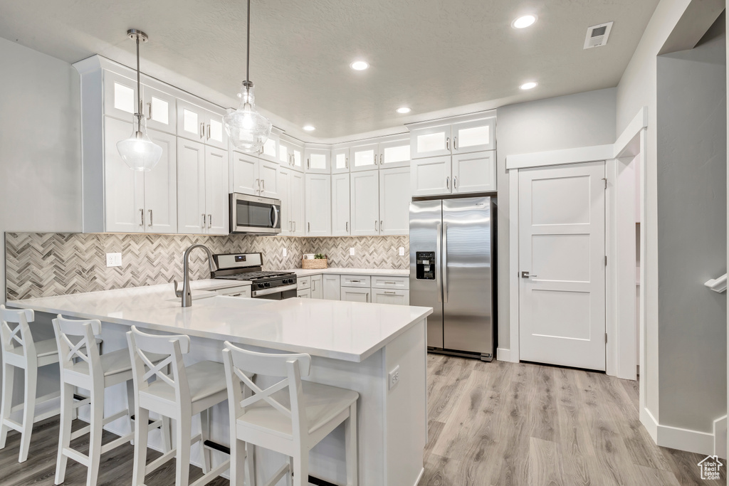 Kitchen featuring light hardwood / wood-style floors, stainless steel appliances, and white cabinets